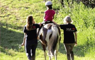 SPUR employees helping child ride a horse