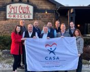 Group holding up CASA flag in front of Salt Creek Grille