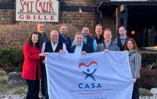 Group holding up CASA flag in front of Salt Creek Grille