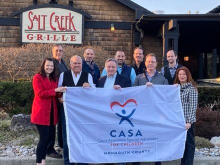 Group holding up CASA flag in front of Salt Creek Grille