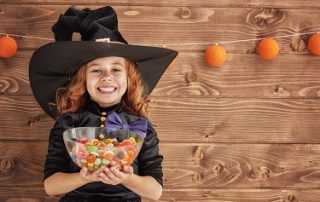 Little girl dressed like a witch, holding candy