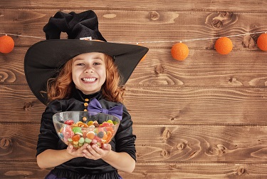 Little girl dressed like a witch, holding candy