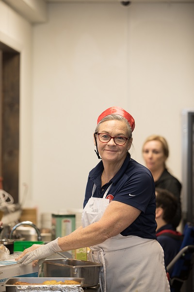 Female employee, with gloves on, preparing food