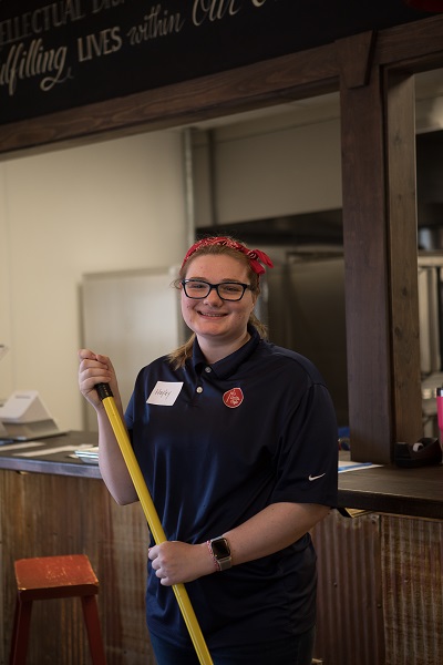 Younger female employee, sweeping out front