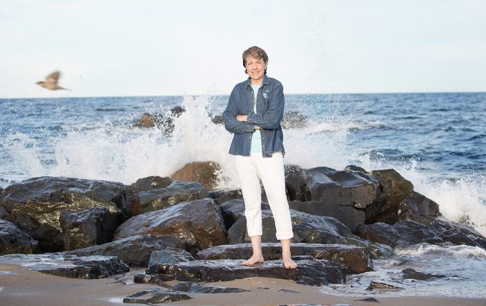 Cindy Zipf standing on rocks; waves crashing