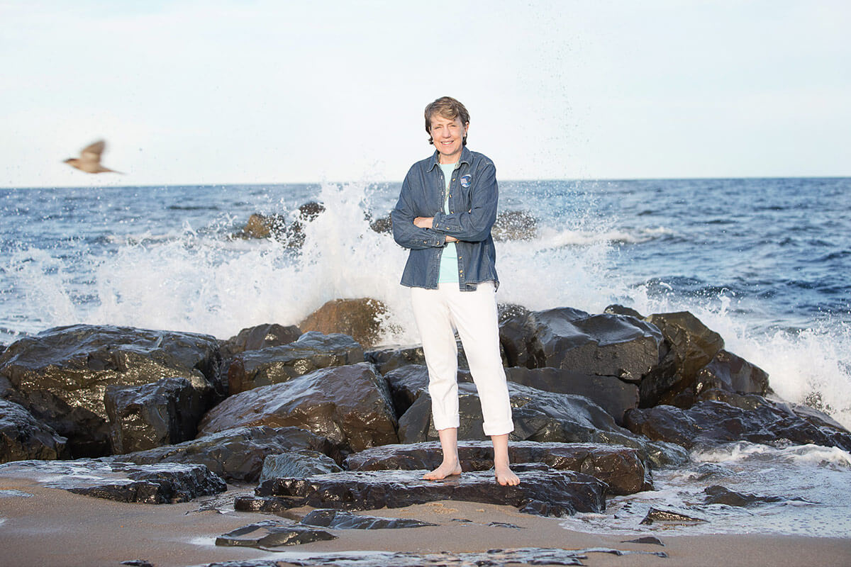 Cindy Zipf standing on rocks; waves crashing