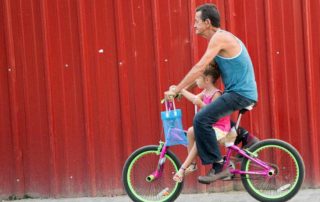 Man riding a bike with a little girl