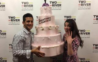 Man and woman holding a large pink wedding cake