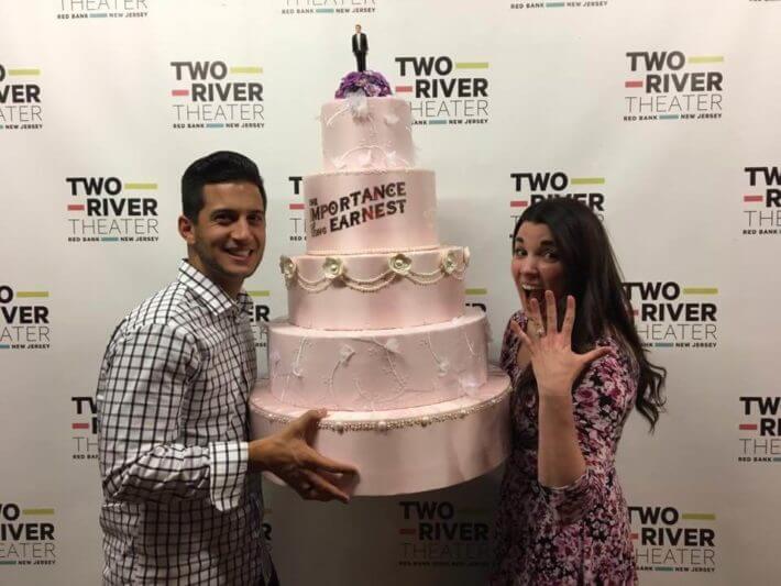 Man and woman holding a large pink wedding cake