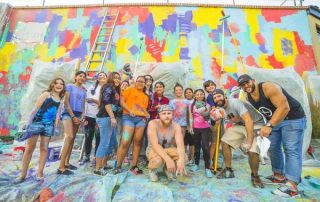 Large group of Red Bank mural [ainters posing in front of colorful wall