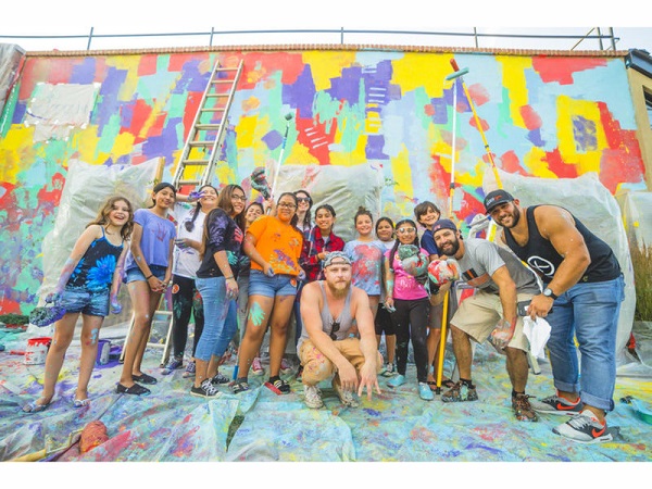 Large group of Red Bank mural [ainters posing in front of colorful wall