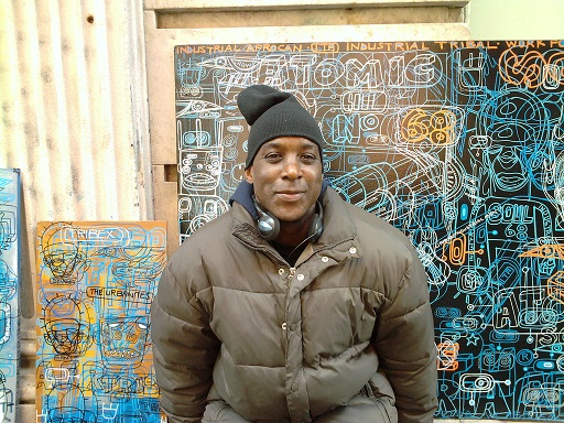 Red Bank mural painter, Ron posing in front of graffitied wall