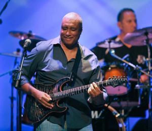 Bernie Williams playing guitar on stage, blue background