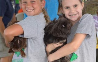 Two little girls holding bunnies at the Livestock Expo