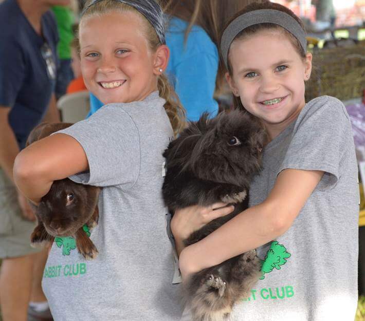 Two little girls holding bunnies at the Livestock Expo